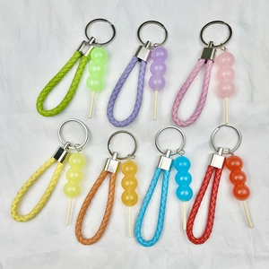 Colorful mini pool ball keychains with braided faux leather straps on a white fabric base