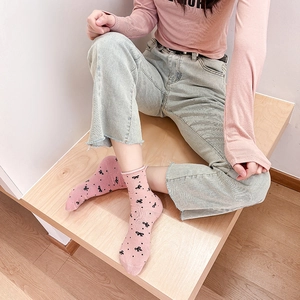 Close-up of pink cotton socks with black bow pattern worn by a model on wooden steps