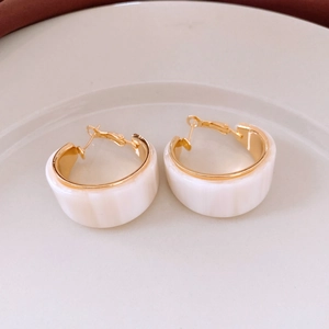 Top view of white resin C-shaped hoop earrings with 18K gold plated metal lining