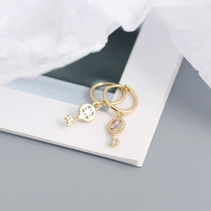 Detail of gold clover key hoop earrings with round cut stones and cutout pattern