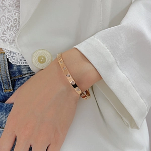 Close-up of gold heart-shaped bangle with embedded crystals worn by a model