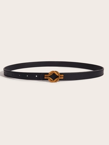 Detail of slim black leather belt with a golden twisted buckle on a beige background