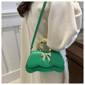 Green PU leather bag with wave edges and gold bow metal handle shown on a model