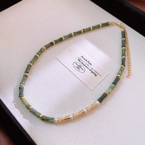 Detail of green bamboo-shaped beads necklace with gold accents and small pearls