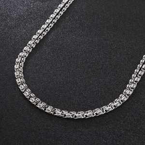 Detailed close-up of a silver stainless steel box chain necklace on black surface