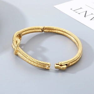 Minimalist gold-plated knot bangle featuring a unique snake bone texture and clasp closure