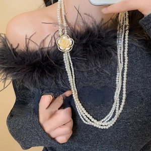 Detail of layered pearl necklace with a vintage gold camellia pendant and floral charm