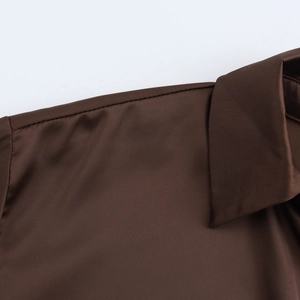 Detailed close-up of smooth brown satin fabric texture on shirt shoulder and collar