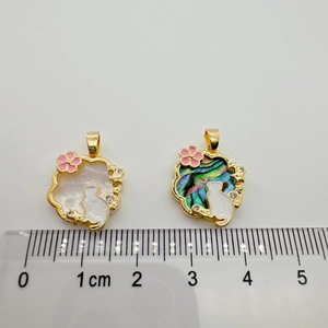 Macro detail of cat pendants with abalone shell and gold edges showing size on ruler