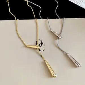 Detail of minimalist gold and silver teardrop pendants on elegant snake chains