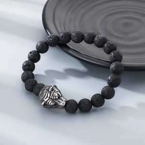 Lava rock stone bead bracelet featuring a silver tiger head charm on a textured surface