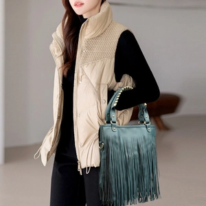 Detail showing a stylish green fringe shoulder bag paired with a beige quilted vest