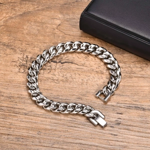 Detailed view of silver thick Cuban link chain bracelet on a rustic wood surface