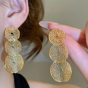 Detail shot of gold triple layered hollow round earrings on model with metallic finish