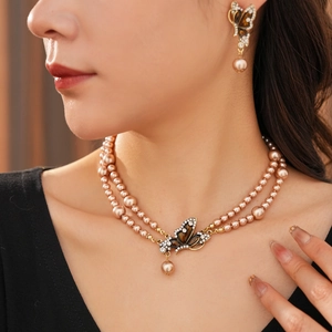 Detail of vintage double-layer pearl necklace with rhinestone butterfly pendant and earrings