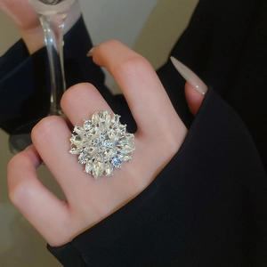 Close-up of sparkling marquise-cut zircon flower ring on hand with elegant dress