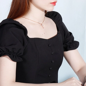 Detail of square neckline and decorative buttons on a black puff sleeve dress