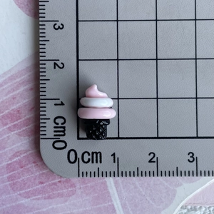 Macro shot of 1.5cm pink ice cream resin charms on a measuring grid for DIY crafts