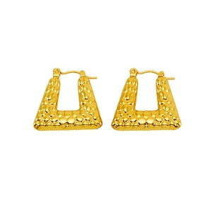 Macro shot of gold-plated trapezoid hoop earrings with hammered textured metal surface