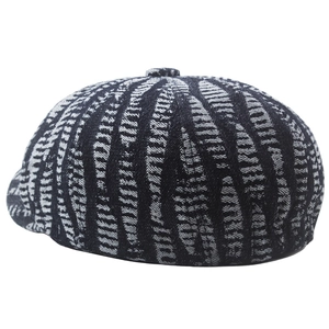 Detail of classic newsboy cap featuring black and white woven pattern and top button