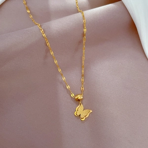 Detail of a golden butterfly pendant on a ripple chain over soft purple silk fabric