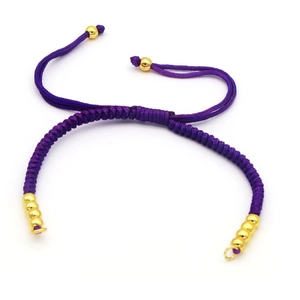 Detail of a handmade purple braided bracelet with adjustable golden bead closures