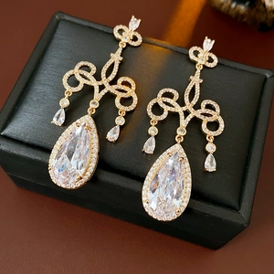 Vue macro de boucles d'oreilles en or avec zircons étincelants sur un coffret noir