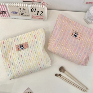 Vue à plat de trousses de maquillage en tweed rose et crème avec écussons de chiens
