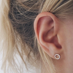 Minimalist hollow round stainless steel stud earrings shown worn on an ear for size
