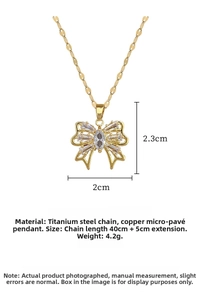 Detailed view of hollow bow pendant necklace with crystals on gold titanium steel chain