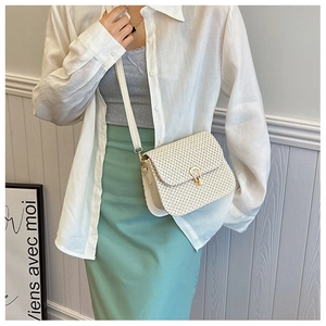 Detail of white woven straw crossbody bag with elegant golden teardrop metal lock