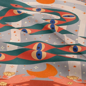 Detail of bohemian tapestry featuring surreal eye and moon pattern on woven fabric