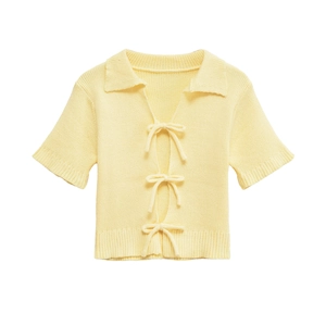 Detail of light yellow knit polo cardigan with bow ties and ribbed texture details