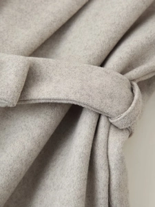 Detailed close-up of gray wool coat texture with a stylish waist tie-up knot belt