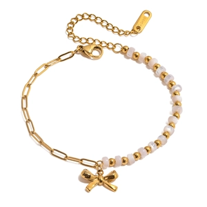 Detail of 18K gold stainless steel bracelet with white beads and a bow pendant