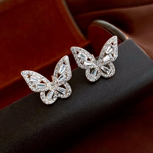Détail des boucles d'oreilles papillon or rose serties de zircons sur support en cuir