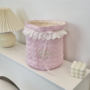 Detailed shot of pink heart-quilted fabric storage basket with white lace trim and bow