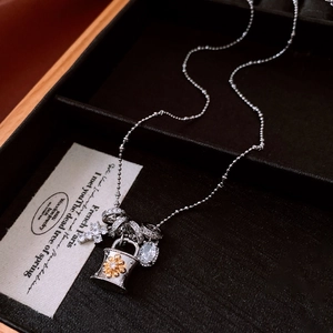 Macro detail of cross and lock pendants with zircon on bead chain in a gift box