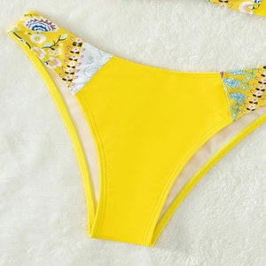 Detail of yellow bikini bottoms featuring vibrant floral side prints on plush white background