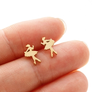 Macro view of small gold ballet dancer silhouette stud earrings held between fingertips
