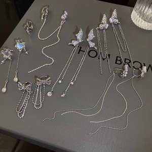 Détail de boucles d'oreilles nœuds argentées avec glands zircons et pierres œil de chat