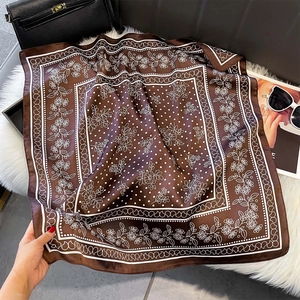 Dettaglio di un foulard quadrato effetto seta con motivi floreali su base soffice