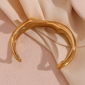 Detailed close-up of a chunky 18K gold-plated cuff bracelet with molten lava texture