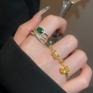 Detail of luxury gold rings featuring green oval and yellow rectangular zircon gemstones
