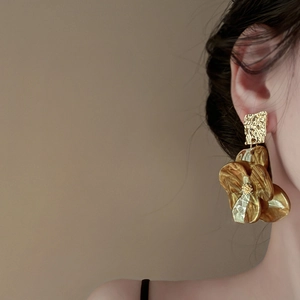 Detailed view of amber resin flower earrings with gold textured metal on model