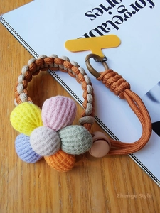 Macro detail of hand-knitted colorful flower charms on a woven phone wrist strap