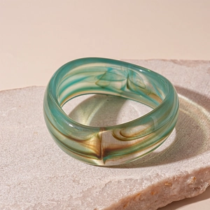 Macro shot of thick geometric acrylic bangle featuring green and amber marbled texture
