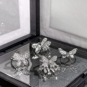 Macro detail of four silver butterfly rings with sparkling zircons and a tassel charm