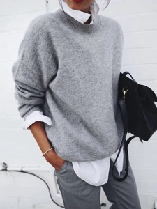 Detail of grey knitted long sleeve sweater layered over a white shirt in street style