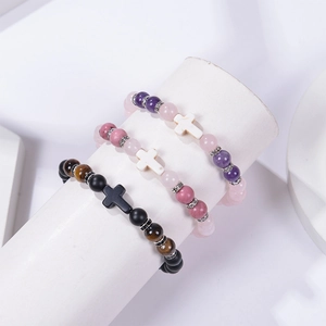 Détail de bracelets en perles 8mm avec pendentif croix et zircons sur un support bijoux